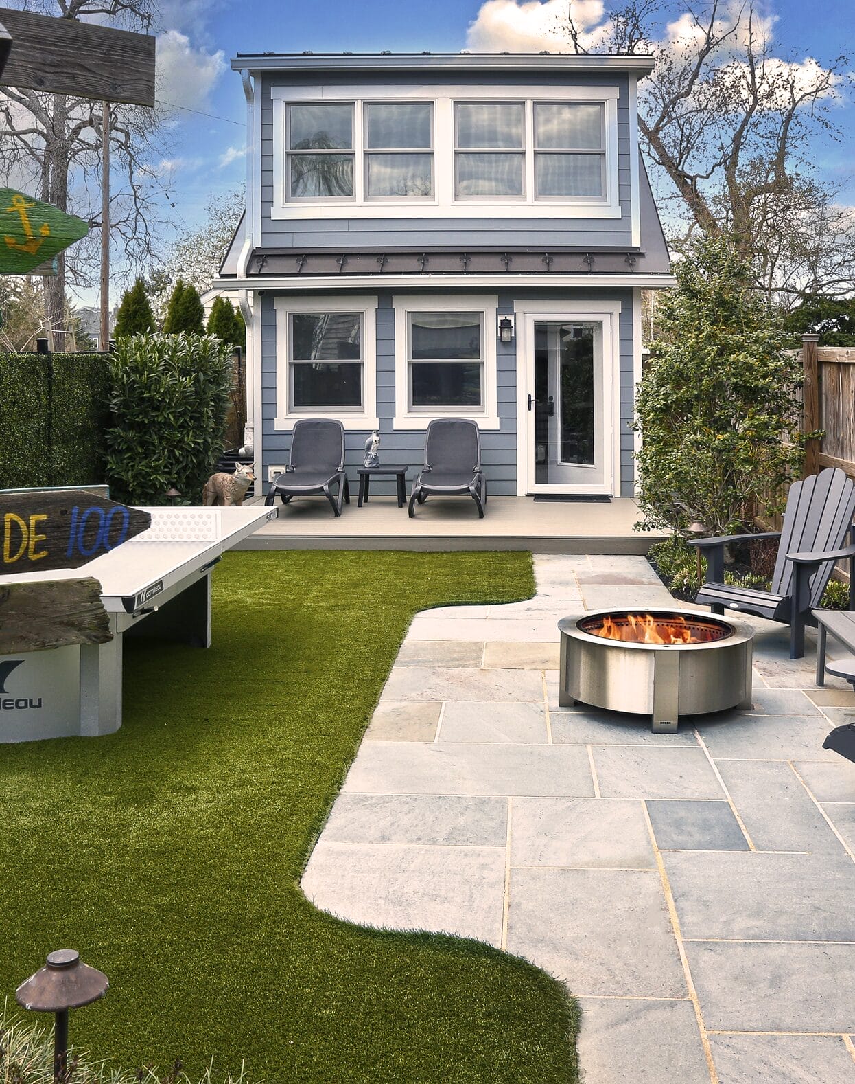 Ridge landscaping backyard with stone patio, fire pit, and turf lawn.