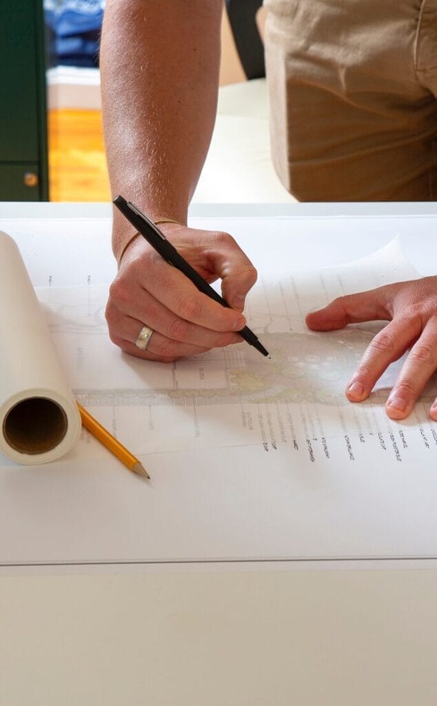 Hand holding a pen writing notes, representing Ridge planning and designing outdoor spaces
